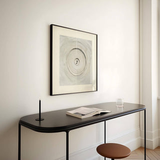 Surrealism posters framed print with concentric sand circles in beige and grey above a black console table with a candle and glass