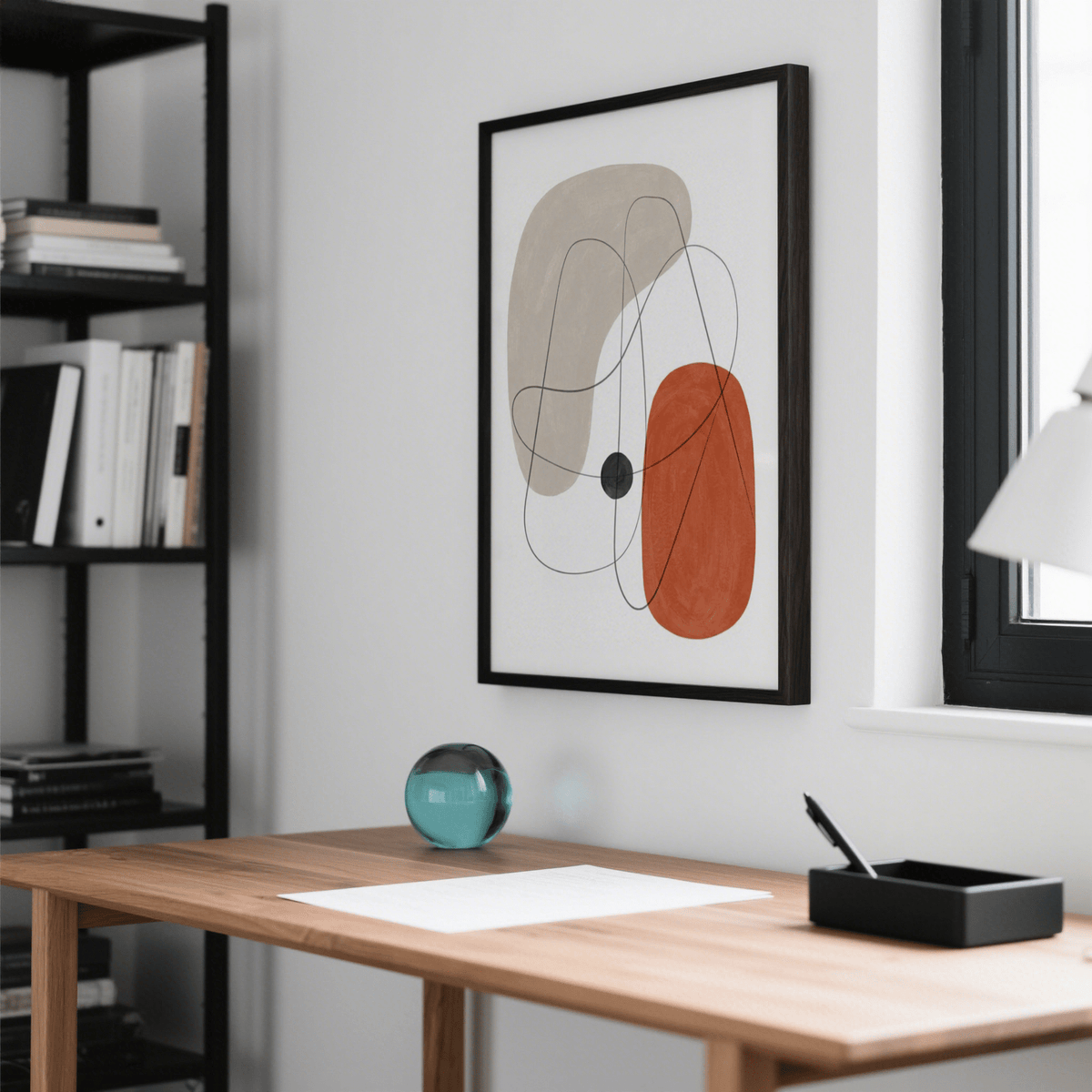 Abstract wall poster with organic shapes in beige and rust above a wooden desk with a glass orb