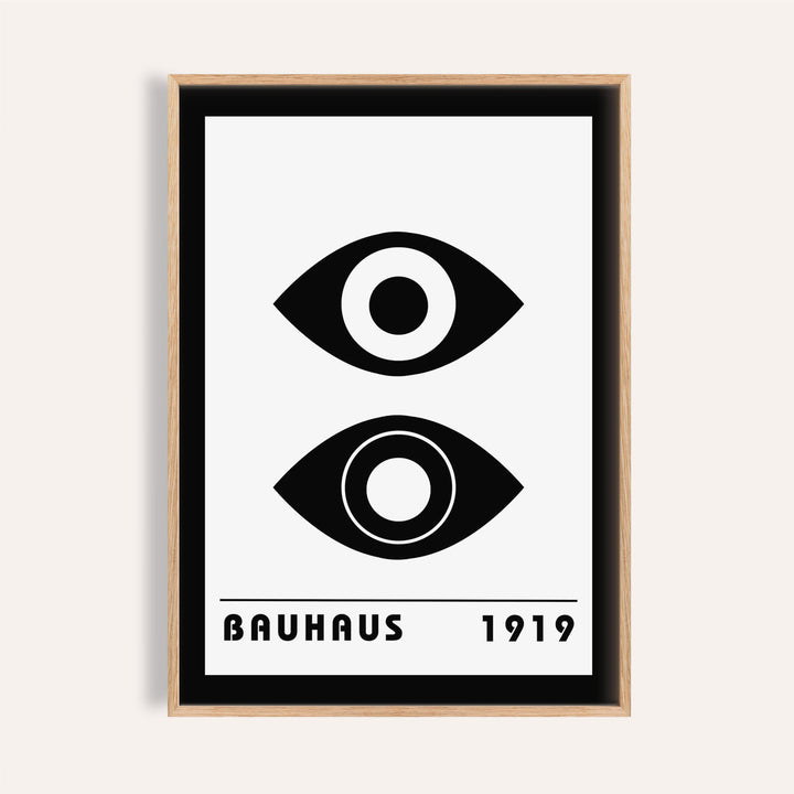 Bauhaus art print of stylized black eyes with minimalist typography in a light wood frame