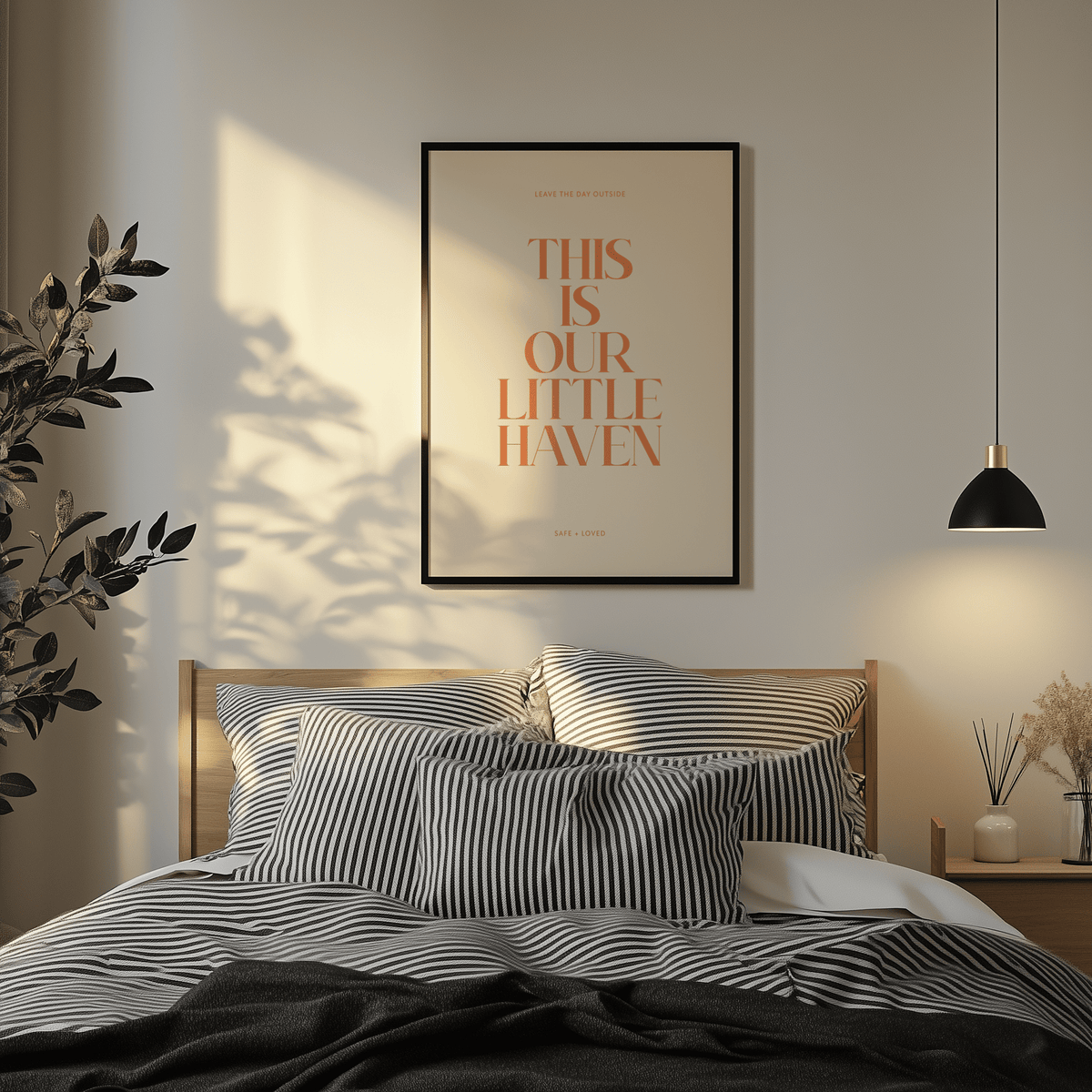 Typography art print with motivational quote in orange and beige above a bed with striped bedding and a black lamp