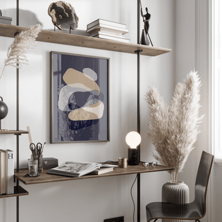 Abstract Art Shapes print on a wall in a study with beige and navy blue shapes alongside a desk and pampas grass