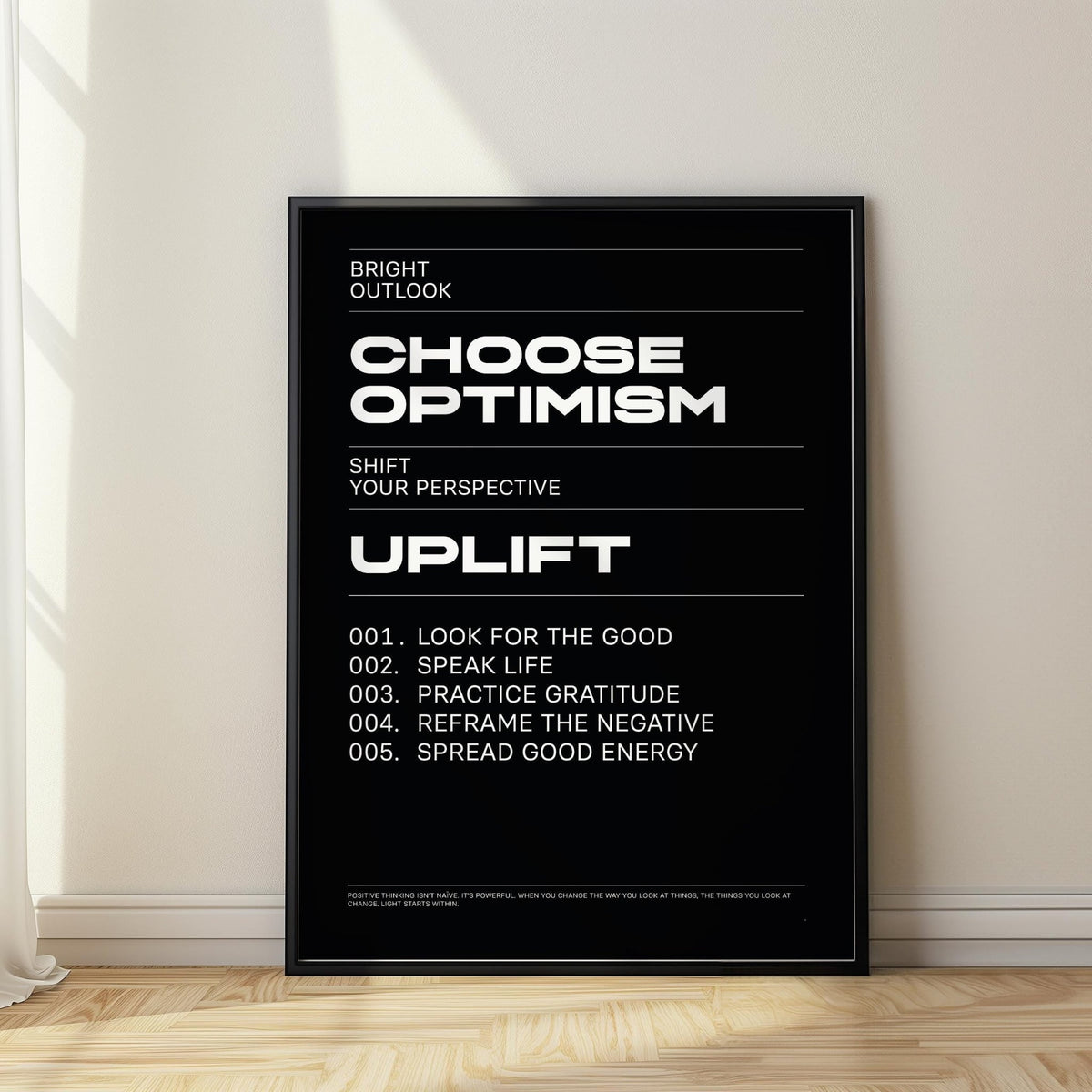 Affirmation Print leaning on wooden floor with black background and white text lit by natural light