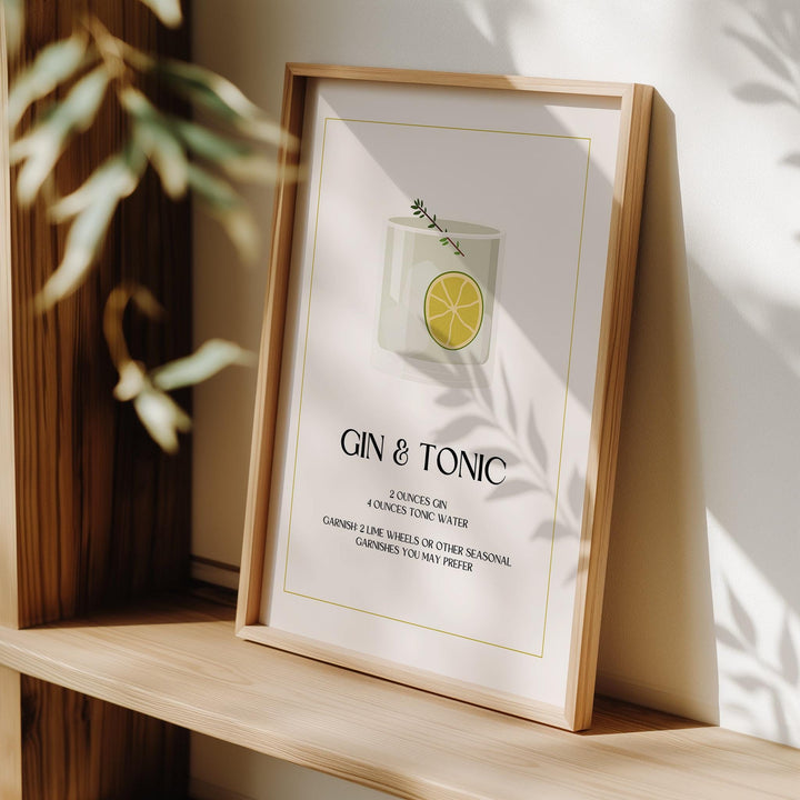 Framed Gin and Tonic wall art with minimalist illustration and typographic style leaning on a wooden shelf