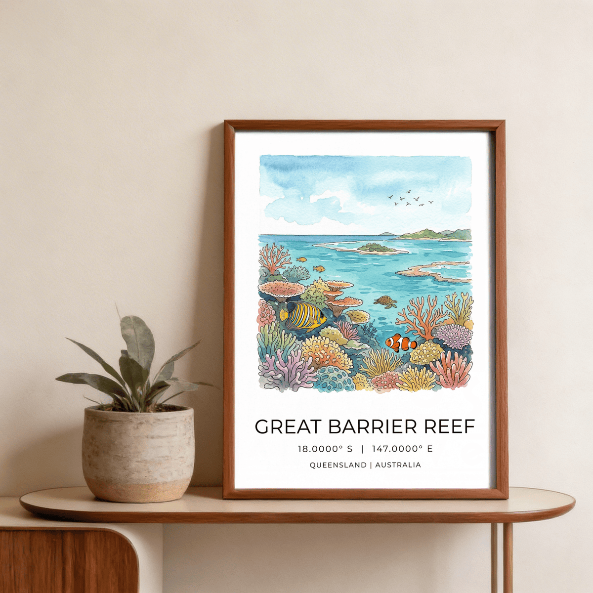 Great Barrier Reef art print in a wooden frame with colourful coral reef and fish next to a plant on a table