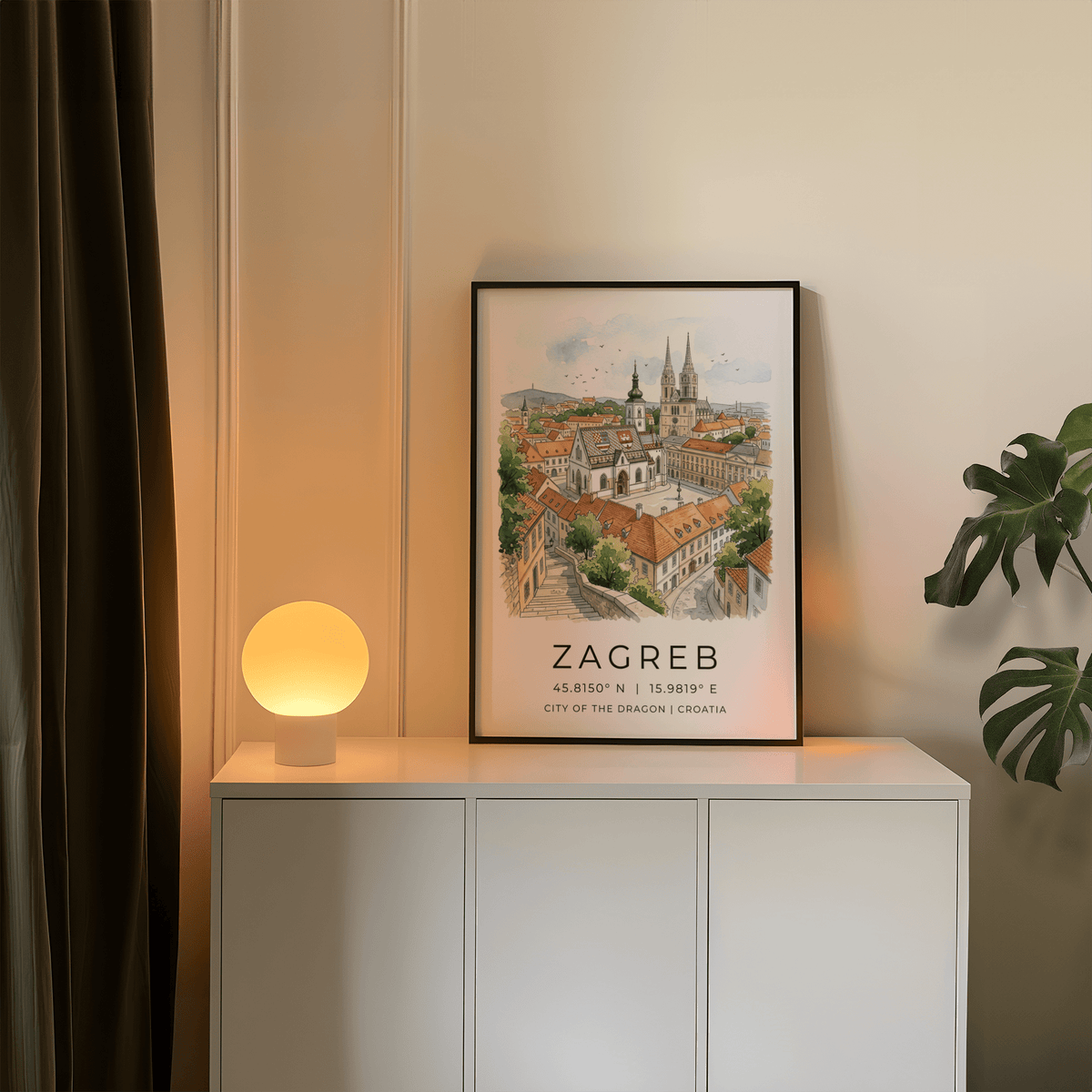 Print on a wall of Zagreb City art print in a black frame with a glowing lamp on the cabinet