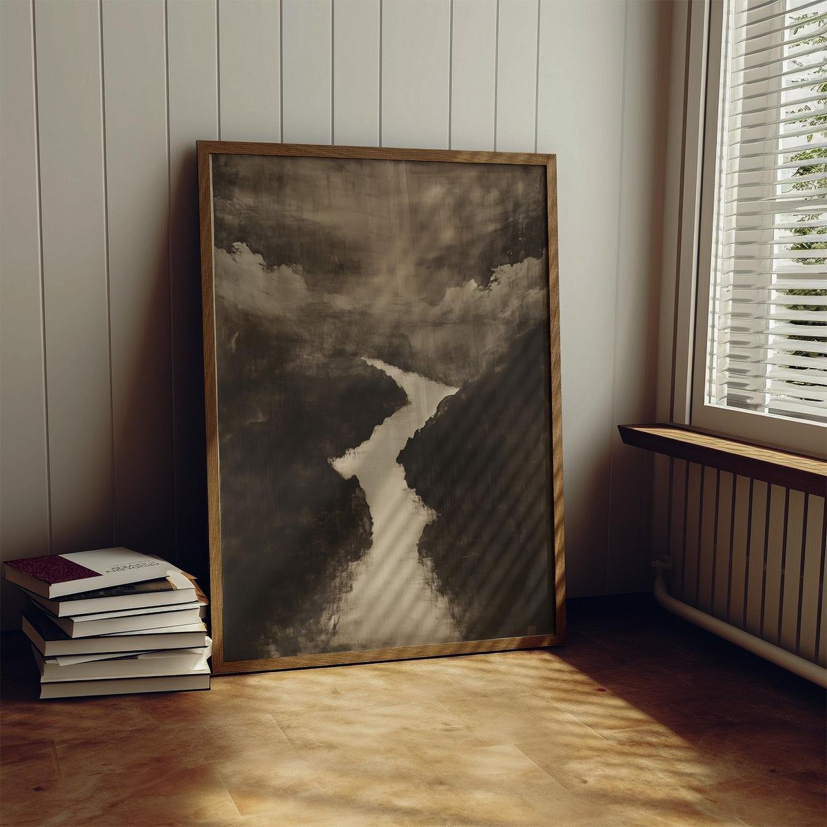 Print leaning on the floor of Sumi e Art river landscape with a muted brown and cream palette next to a stack of books