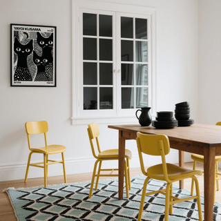 Black Cats Poster on a white wall in a dining room with yellow chairs and wooden table