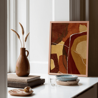 Abstract Earth Tones Print leaning on a white windowsill with pottery and dried grasses nearby