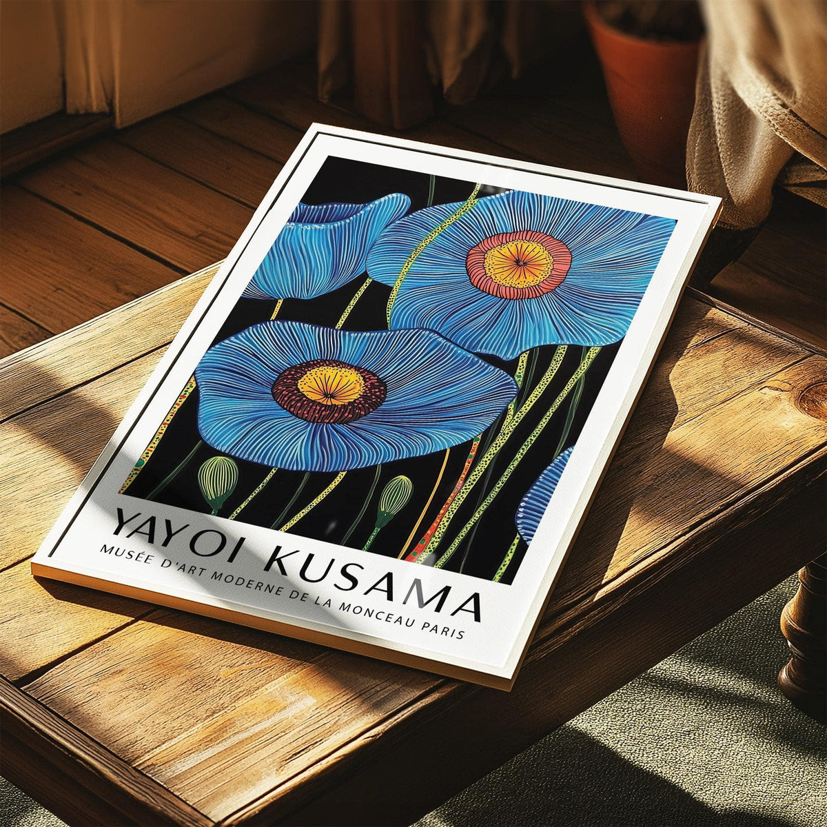 Big Flower wall art of blue poppy flowers with yellow and red centres laid on a wooden table