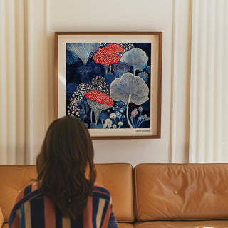 Framed Mushroom Poster wall art of spotted mushrooms in blue and red above a tan sofa in a living room