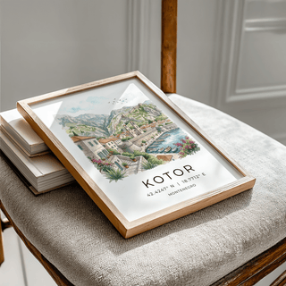Kotor Landscape Art Print in a wooden frame leaning on a chair with grey fabric and books