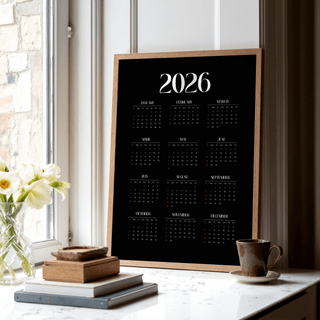 Modern Calendar Print minimalist 2026 calendar with black background leaning on a window ledge near a cup