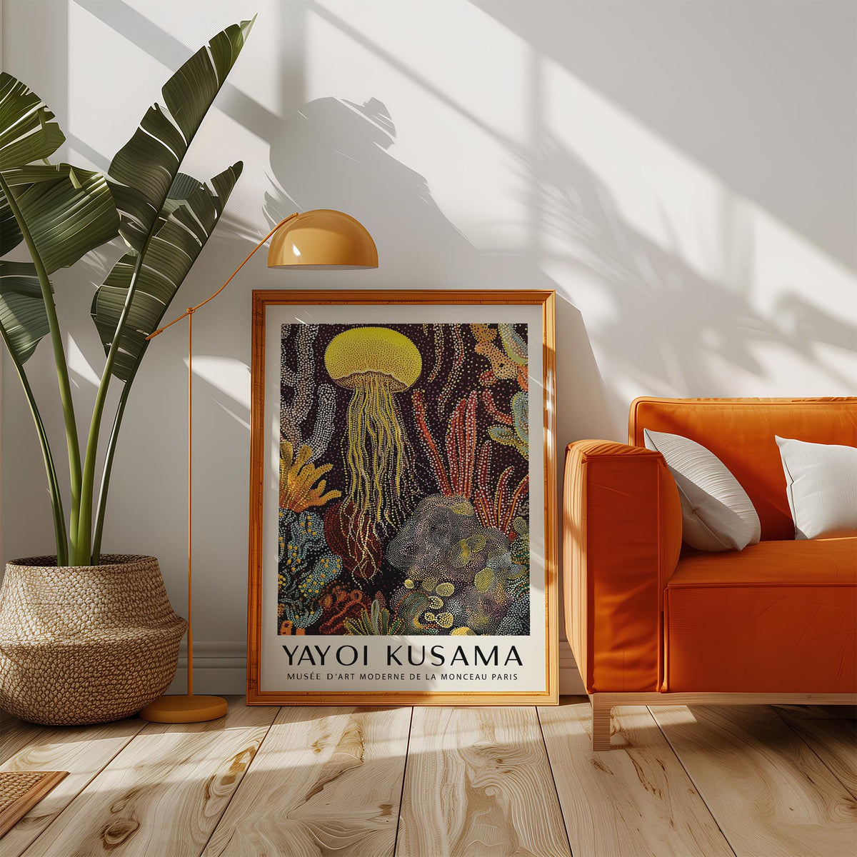 Jellyfish poster leaning on a wooden floor beside an orange sofa and a large potted plant in natural light
