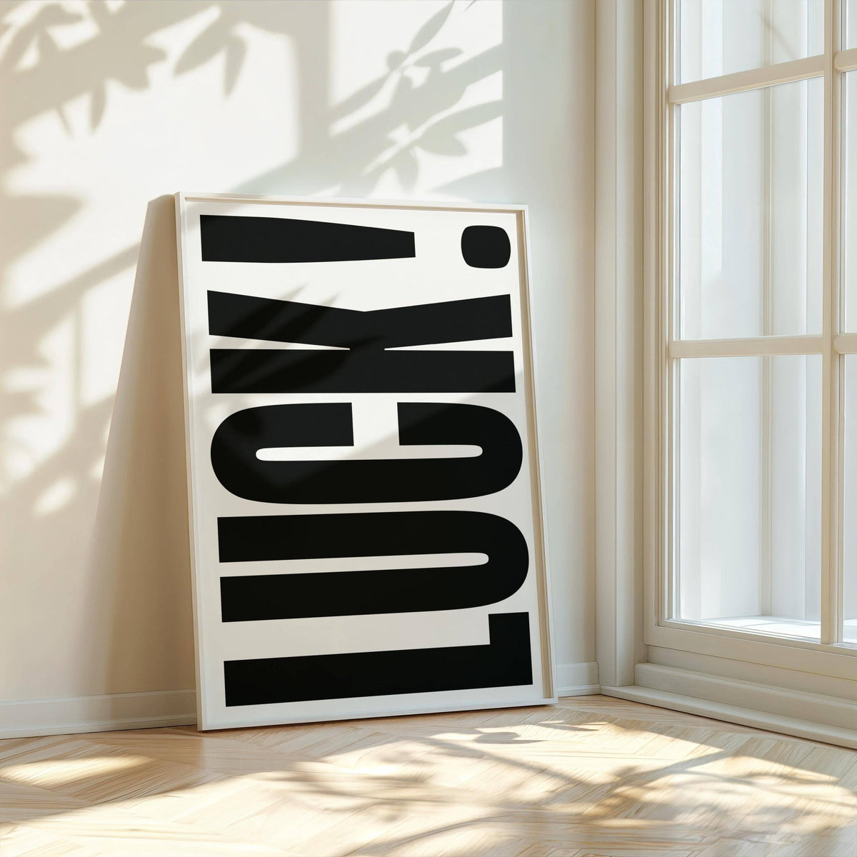 Print leaning on floor with luck typography in black and white by a window with shadows