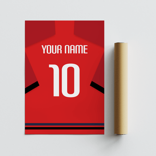 Close-up of a red football shirt poster with black sleeve bands and white typography next to a packaging tube