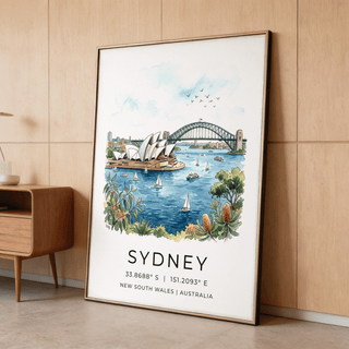 Print leaning on floor shows Sydney Opera House and Harbour Bridge in blue and green watercolour alongside text with coordinates