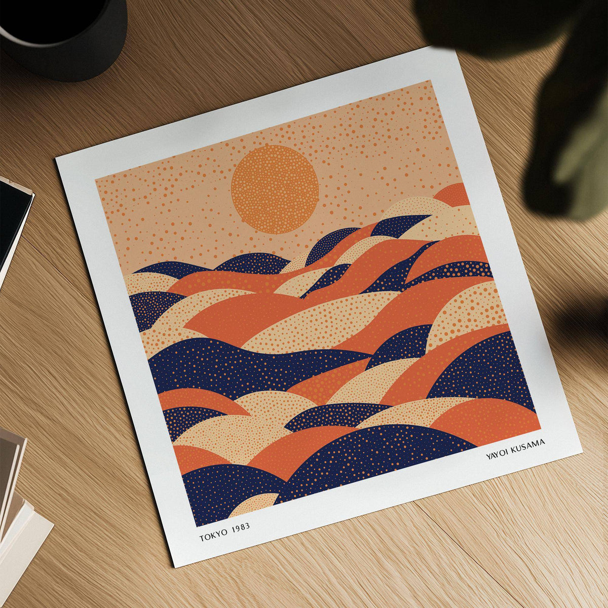 Abstract wall art colourful with orange and navy polka dot hills on a wooden surface next to a plant pot