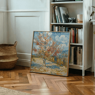 Print leaning on wooden floor with basket and bookcase nearby showing a blossoming tree with blue sky