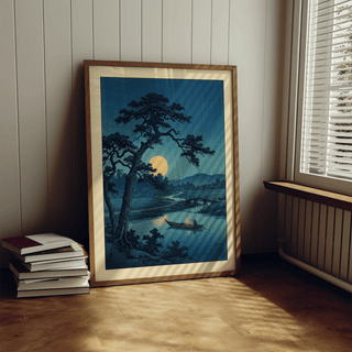 Moonlight Print leaning on a wooden floor by a sunlit window with white blinds and stack of books