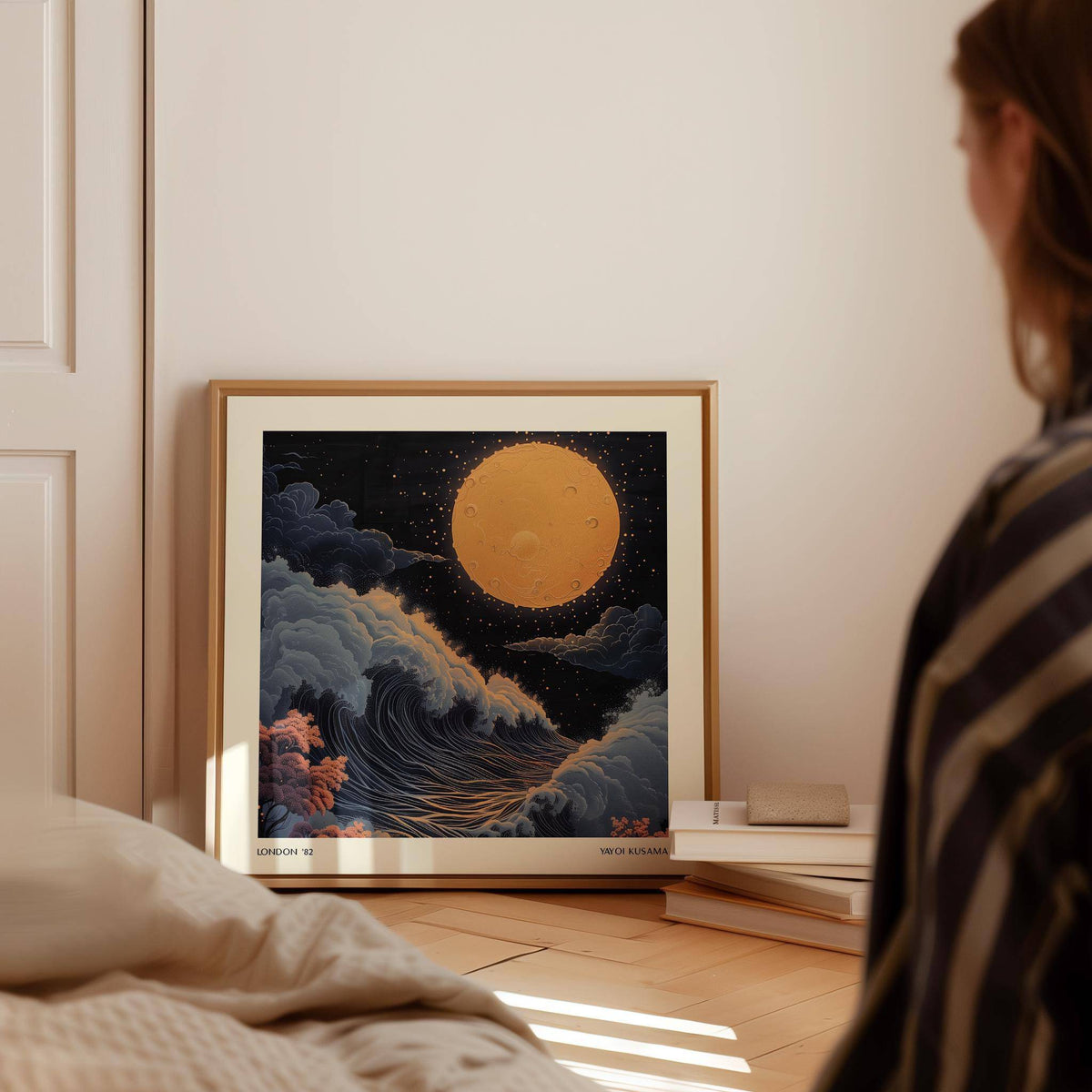 Japanese Art Pictures print leaning on the floor with a large orange moon and swirling clouds beside a book