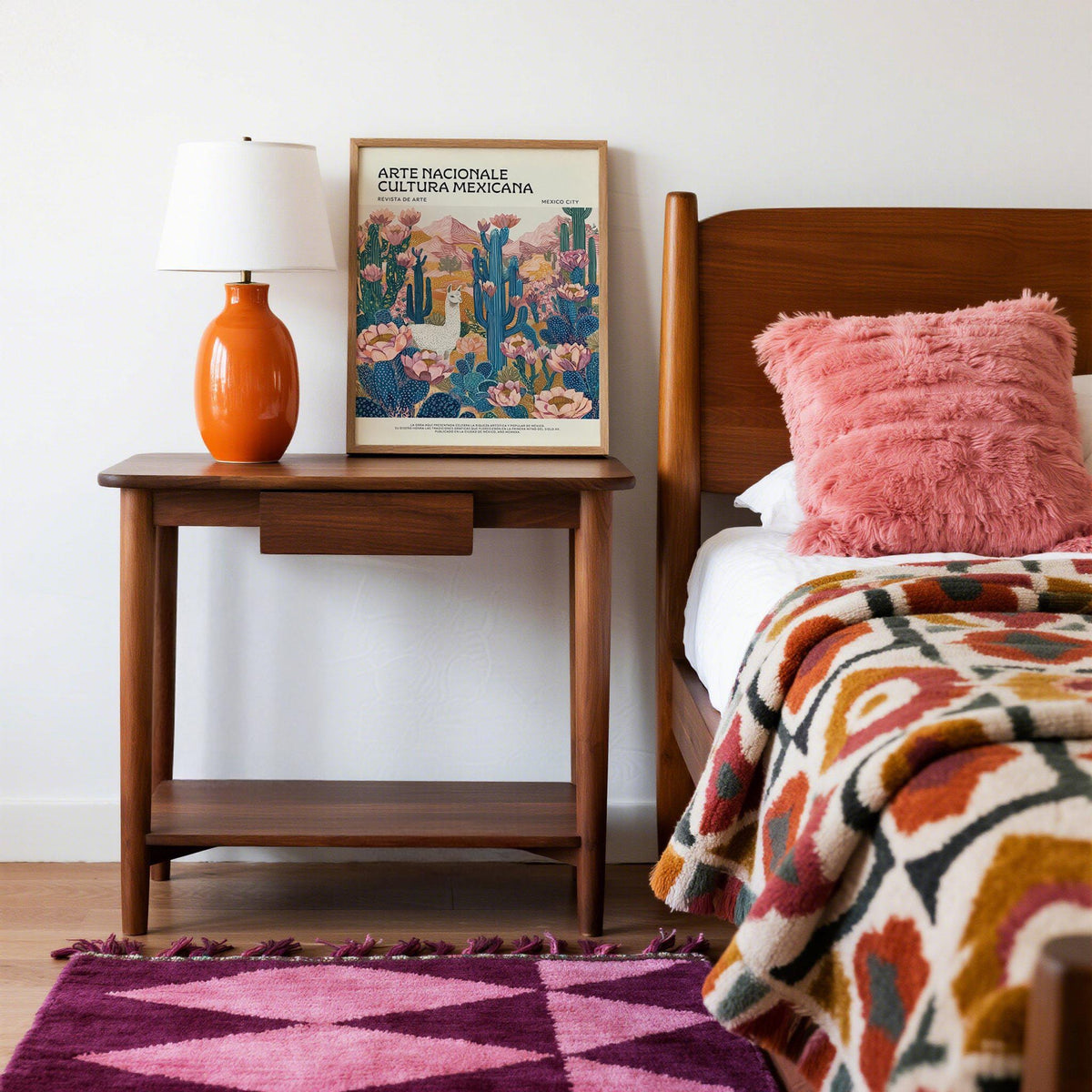 Mexican wall decor print on a bedside table with an orange lamp and pink cushion