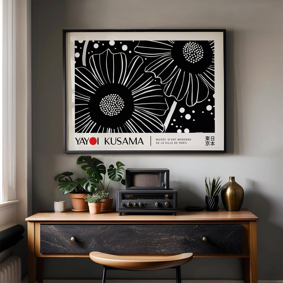Horizontal wall hanging of black and white flowers in minimalist style above a desk with plants and vase