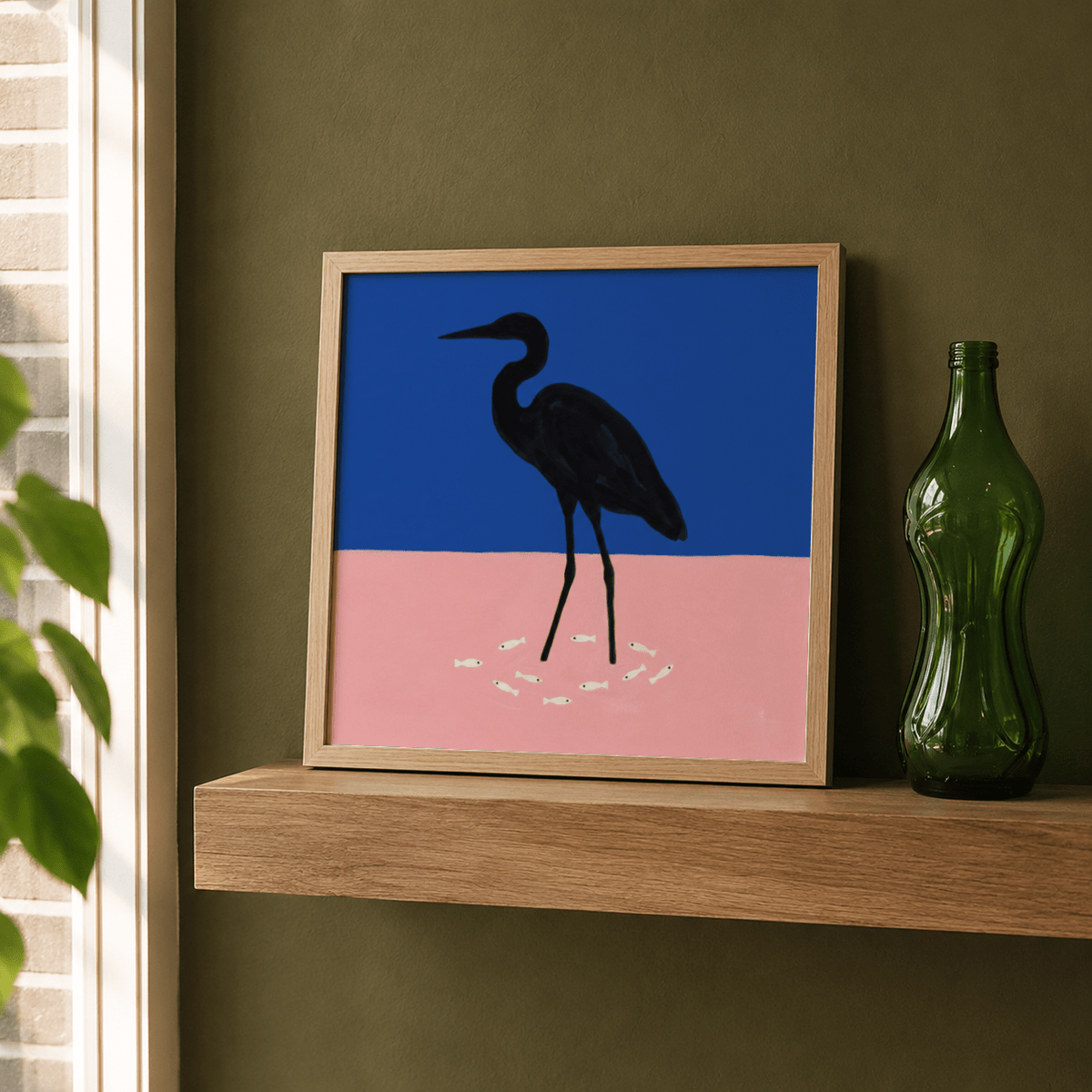 Print leaning on a shelf with heron silhouette on blue and pink background with white fish beside a green bottle