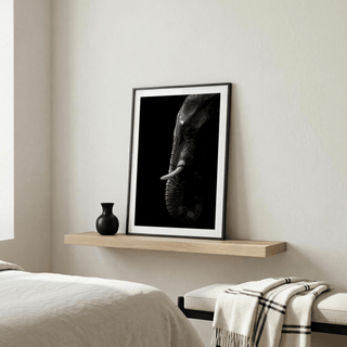 Black Elephant wall art leaning on a floating shelf with a black vase in a bedroom