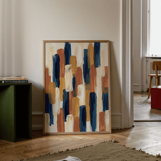 Abstract Color Blocks print leaning on a wooden floor beside a green side table with books