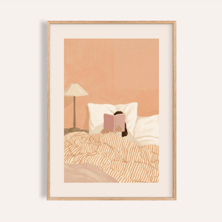 Framed print of a person reading in bed with a peach and beige colour palette