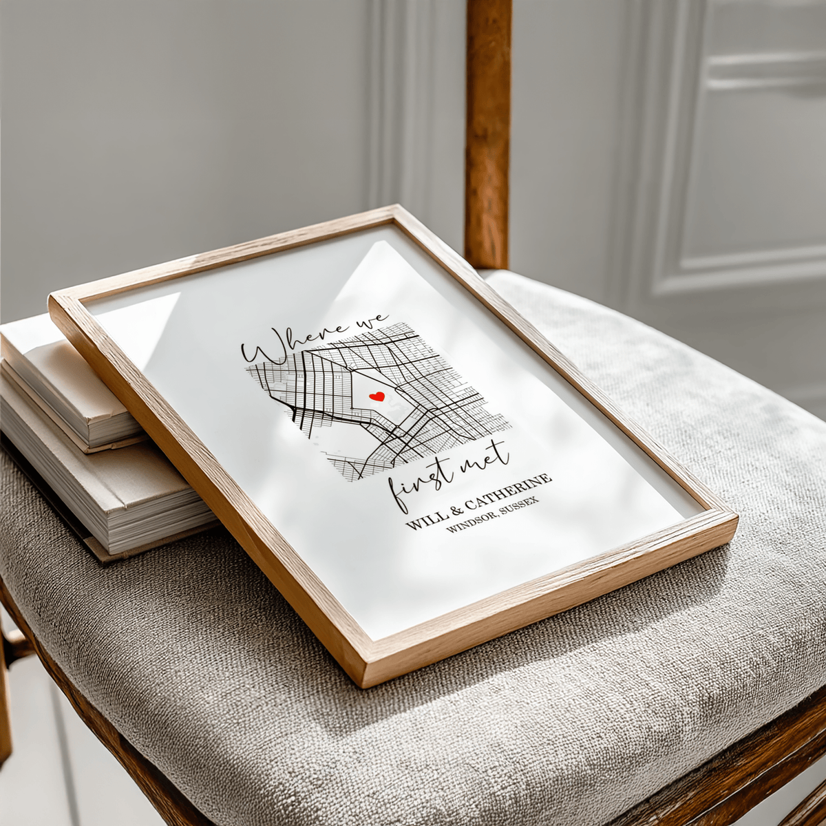 Framed Heart on Map Print with red heart and black map lines on a beige chair next to books