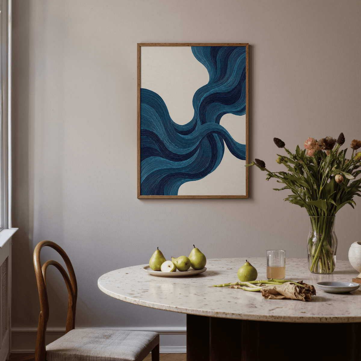 Blue line wall art with flowing blue lines in an abstract style above a dining table with pears and flowers