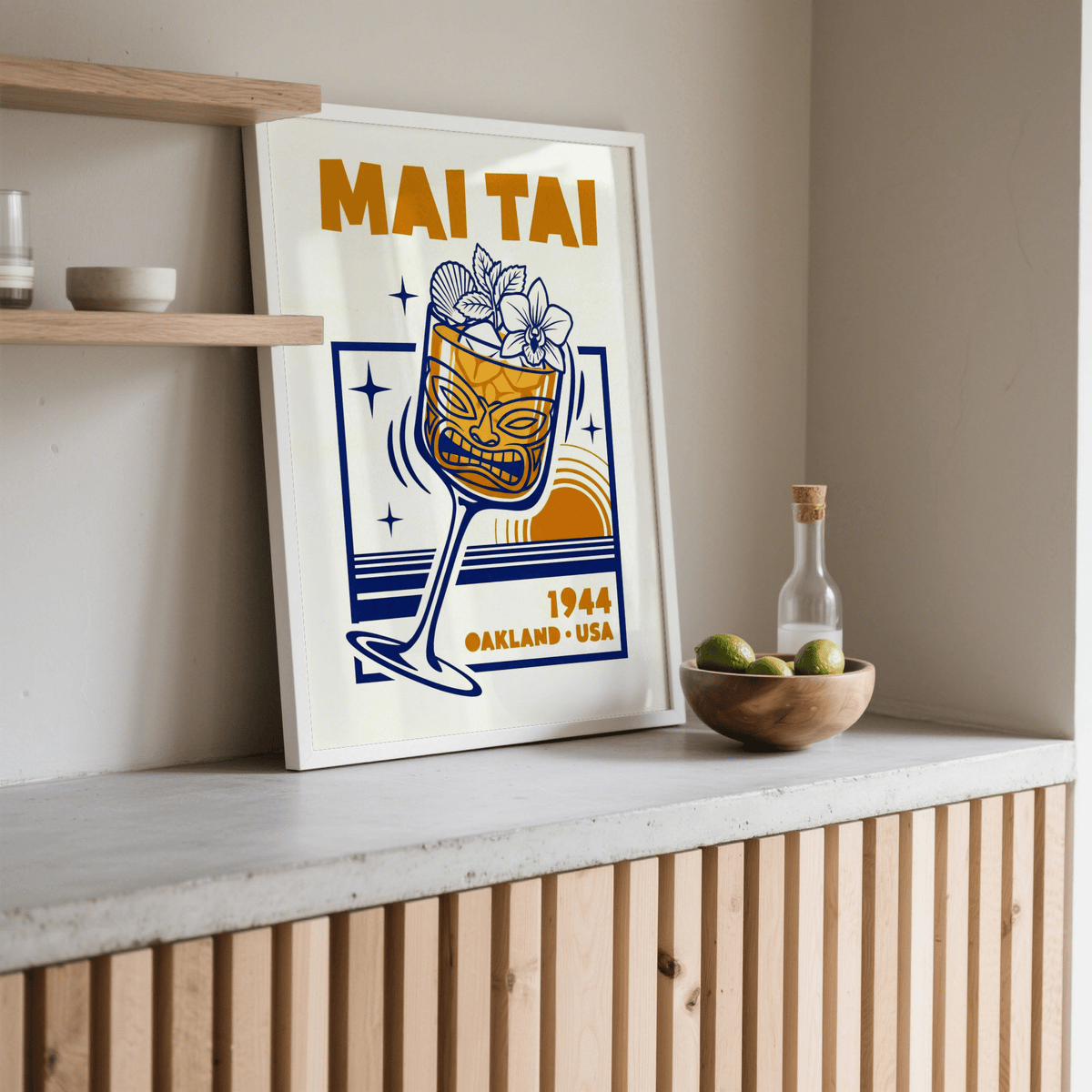 Mai Tai wall art print leaning on a countertop next to a bowl of limes in a neutral room