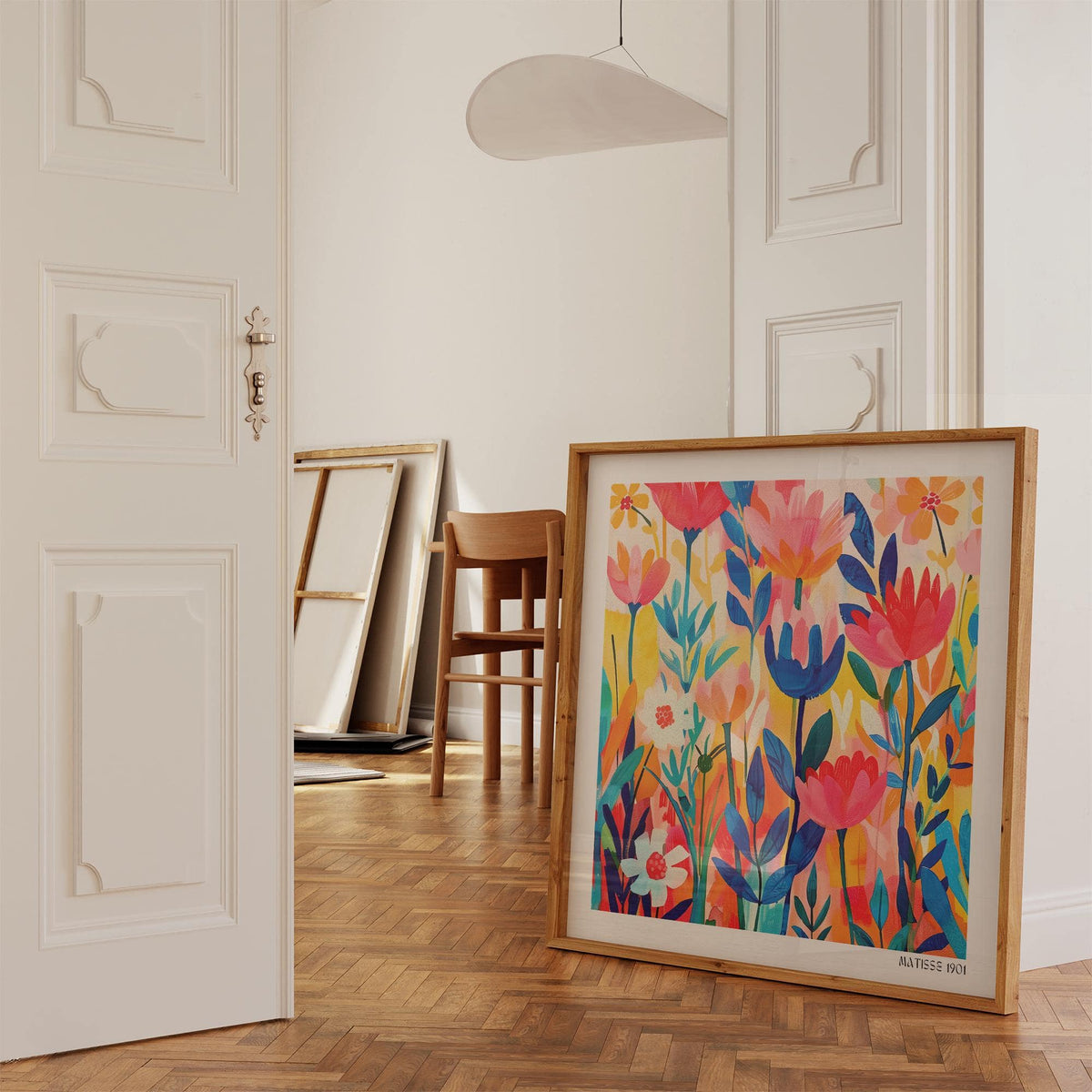 Print leaning on a wooden floor showing colourful minimalist floral illustration with pink and blue flowers and a wooden chair nearby