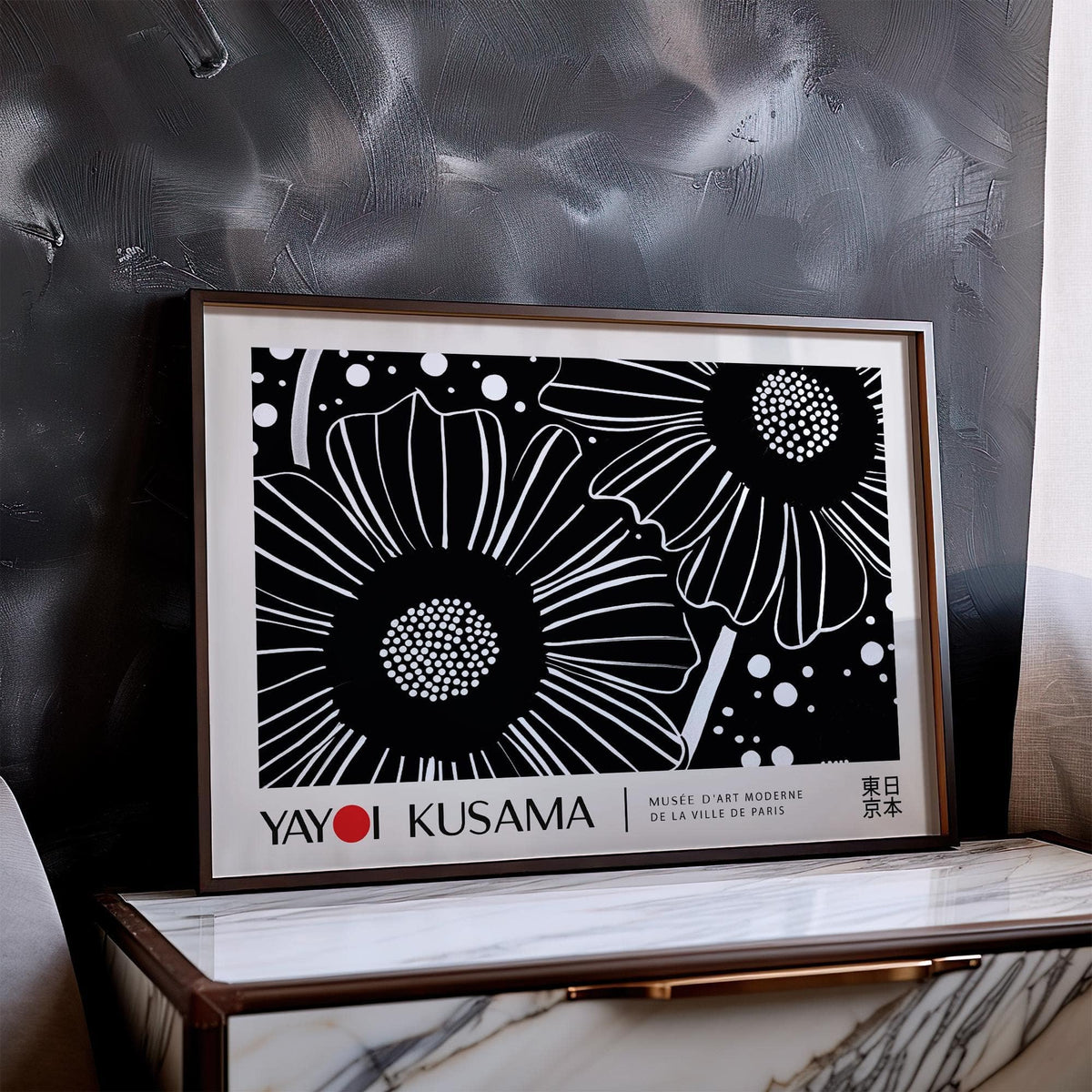 Horizontal wall hanging of black and white flowers leaning on a marble cabinet in front of a textured grey wall