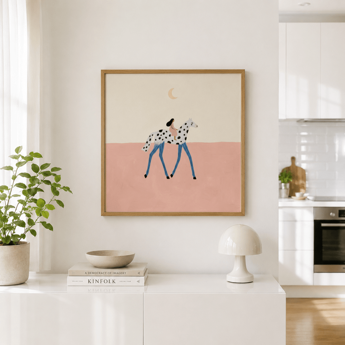 Print on a wall of girl on a spotted horse with blue legs and a crescent moon above on a pale pink background with plant nearby