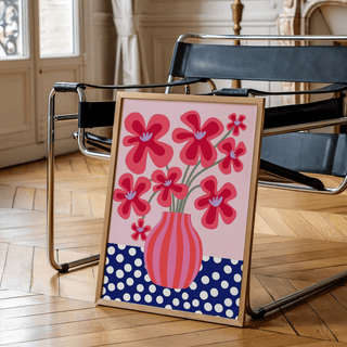 Colorful Flower Poster print leaning on a black chair with wooden floor and curtains visible