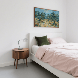Olive Tree Landscape Print above bed with green cushion and wooden bedside table in white bedroom