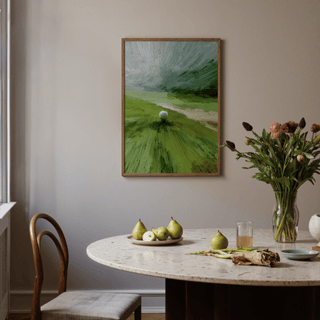 Abstract green wall art of a golf ball on tee in a dining room with a white marble table and pears