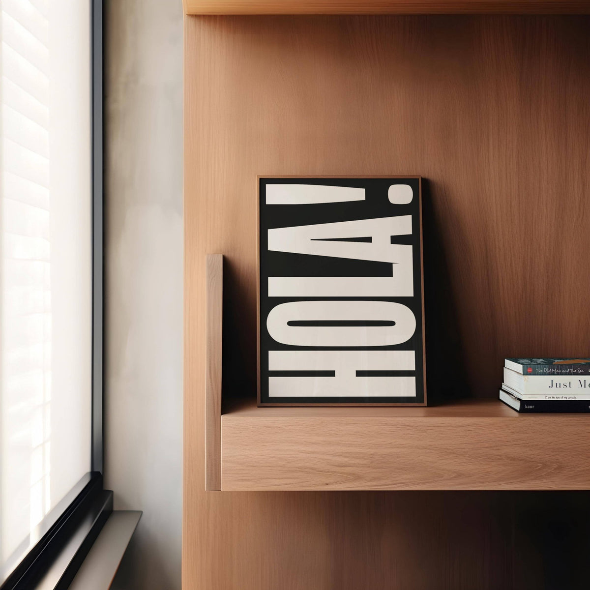 Posters with Typography leaning on a wooden shelf with bold white HOLA text on black background and books beside it