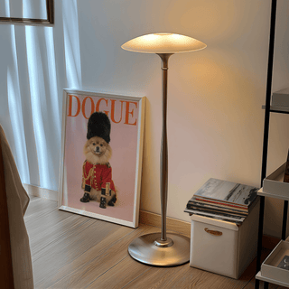 Pomeranian poster print leaning on the floor next to a lit floor lamp with books on a box