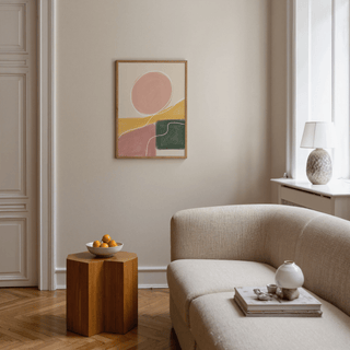 Modern Abstract Print on wall featuring pink circle and green block above wooden side table with bowl of oranges