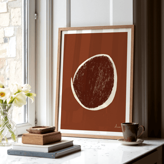 Framed Abstract Earth Tone Art Print with a brown circular shape on a window sill next to a cup and flowers