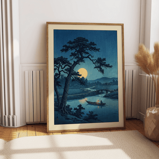 Framed Moonlight Print of a moonlit river scene with blue and yellow tones leaning on a wall near a beige cushion