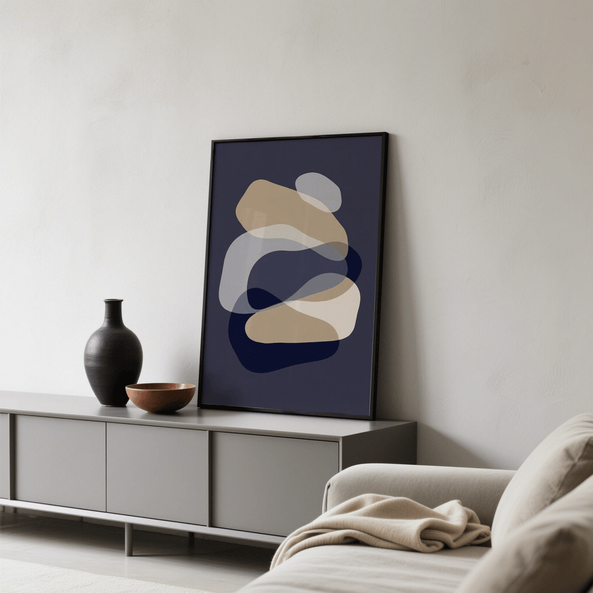 Abstract Art Shapes print leaning on a grey sideboard with a black vase and brown bowl in a living room