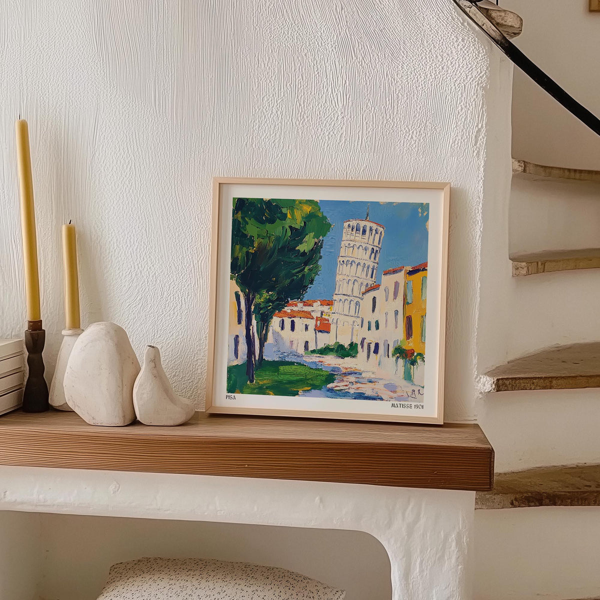 Print leaning on a shelf of the Leaning Tower of Pisa in green and yellow tones with sculptural ornaments nearby