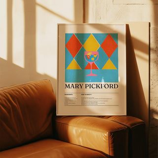 Framed print of a pink cocktail glass with geometric red and yellow diamonds leaning on a leather couch