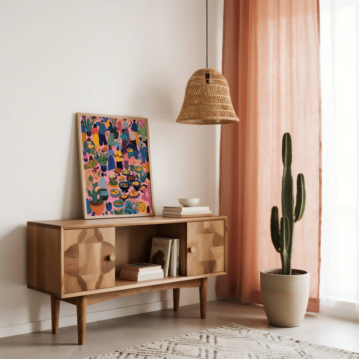 Artwork from Mexico print leaning on a wooden sideboard with a tall cactus by pink curtains