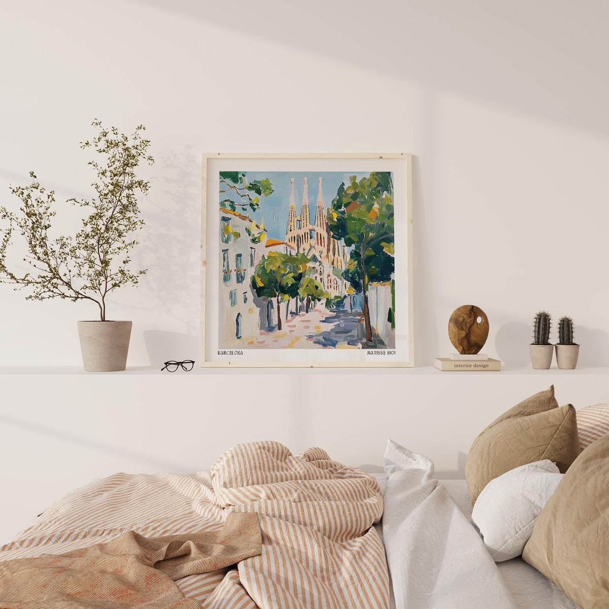 Barcelona Boulevard Poster framed print of the Sagrada Familia with green trees on a white shelf above a bed