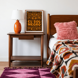 Mexican Culture Art Print leaning on a wooden table with an orange lamp in a bedroom